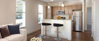 A kitchen with a white counter and bar stools.